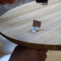Snedkersvend i gang med at samle et egetræsbord. Bordbenene er tappet gennem bordpladen og fastgøres med en kile fra oversiden.