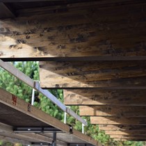 Duften af tjære har gjort sin entre på byggepladsen. Udvendigt træværk ved sommerhusbyggeriet behandles med trætjære.
