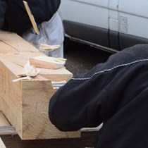 Afbinding. Tømrersvend i gang med afbindingsjernet så spånene bogstaveligt talt flyver om ørene. Der bruges 8x8” tømmer af pommersk fyr i en specialsortering til et nyt bjælkelag i en etageadskillelse